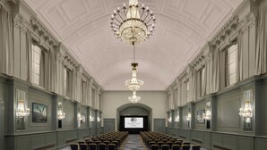 A grand hall with rows of chairs, a large chandelier, and a screen at the front. - Doubletree By Hilton Brighton Metropole (Brighton)