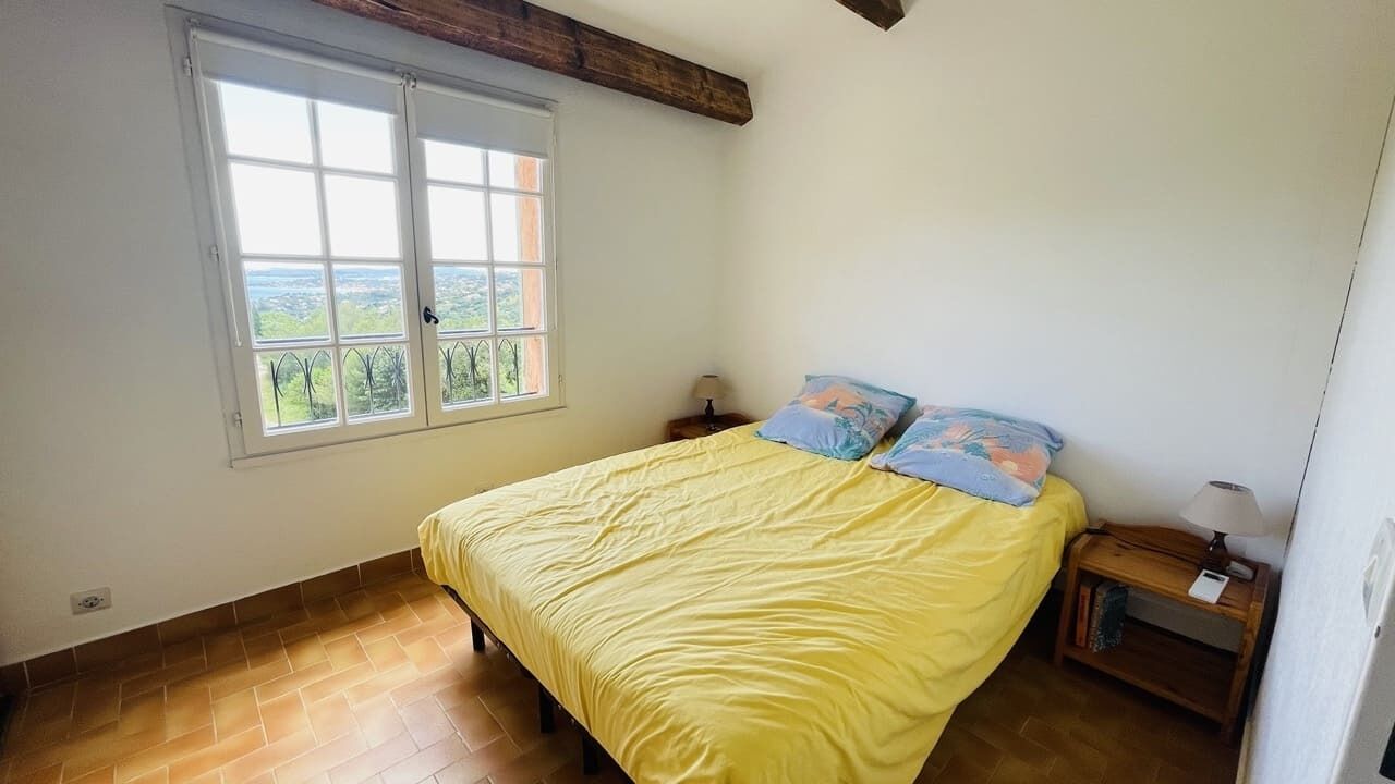Une chambre à coucher avec un lit, une fenêtre donnant sur un beau paysage et une table de chevet avec une lampe.
