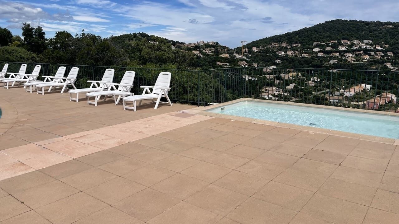 A pool area with lounge chairs and a view of a hillside.