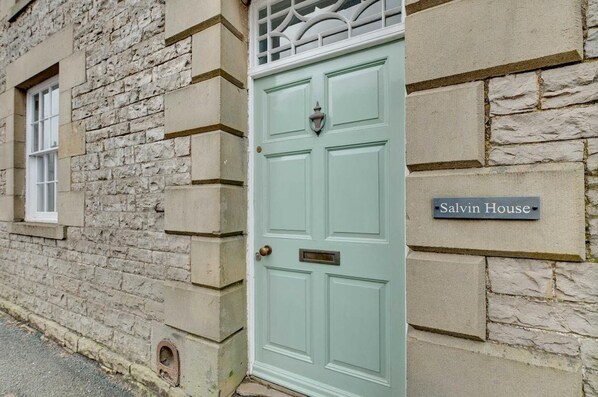A building with a stone facade and a light green door labeled "Salvin House."