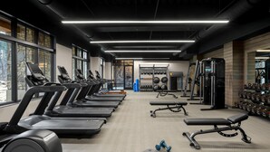 Une salle de sport équipée de tapis de course, de bancs de musculation et de poids libres.
