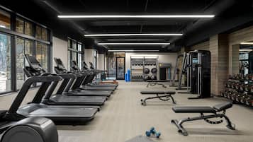 Un gimnasio con cintas de correr, bancos de pesas y pesas sueltas.