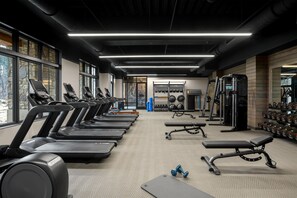 Une salle de sport équipée de tapis de course, de bancs de musculation et de poids libres.