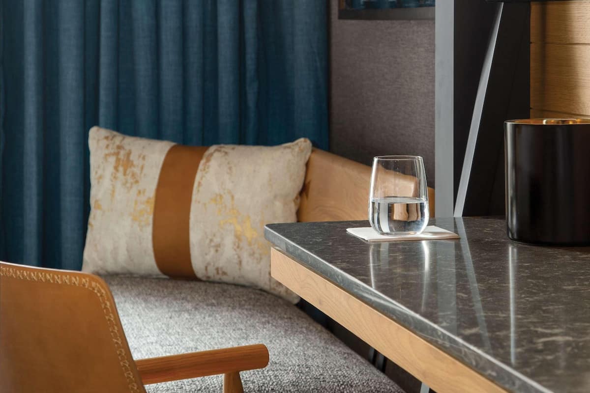 Una habitación moderna con un banco de madera, una mesa de vidrio y un cuadro grande en la pared.