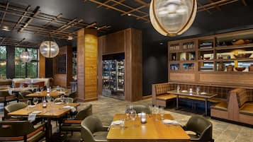 Ein Restaurant mit Holztischen und -stühlen, einer Bar und einer Weinauslage.