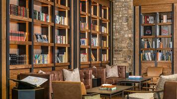 A library with leather seating and bookshelves filled with books.