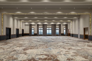 A spacious hotel room with a large carpeted floor, multiple doors, and a view through large windows. - Cloudland Mclemore Resort Lookout Mountain Curio (Rising Fawn)