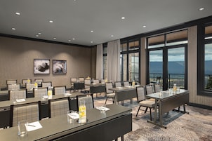 Un salón de conferencias de hotel con mesas, sillas y un amplio ventanal con vistas.