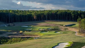 Un parcours de golf dot é de nombreux bunkers et bordé d’une zone boisée en arrière-plan.
