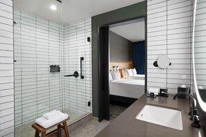 Une salle de bain d’hôtel avec une douche, un lavabo et un miroir.