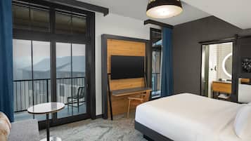 A hotel room with a bed, a desk, a chair, a TV, and a large window with a view.