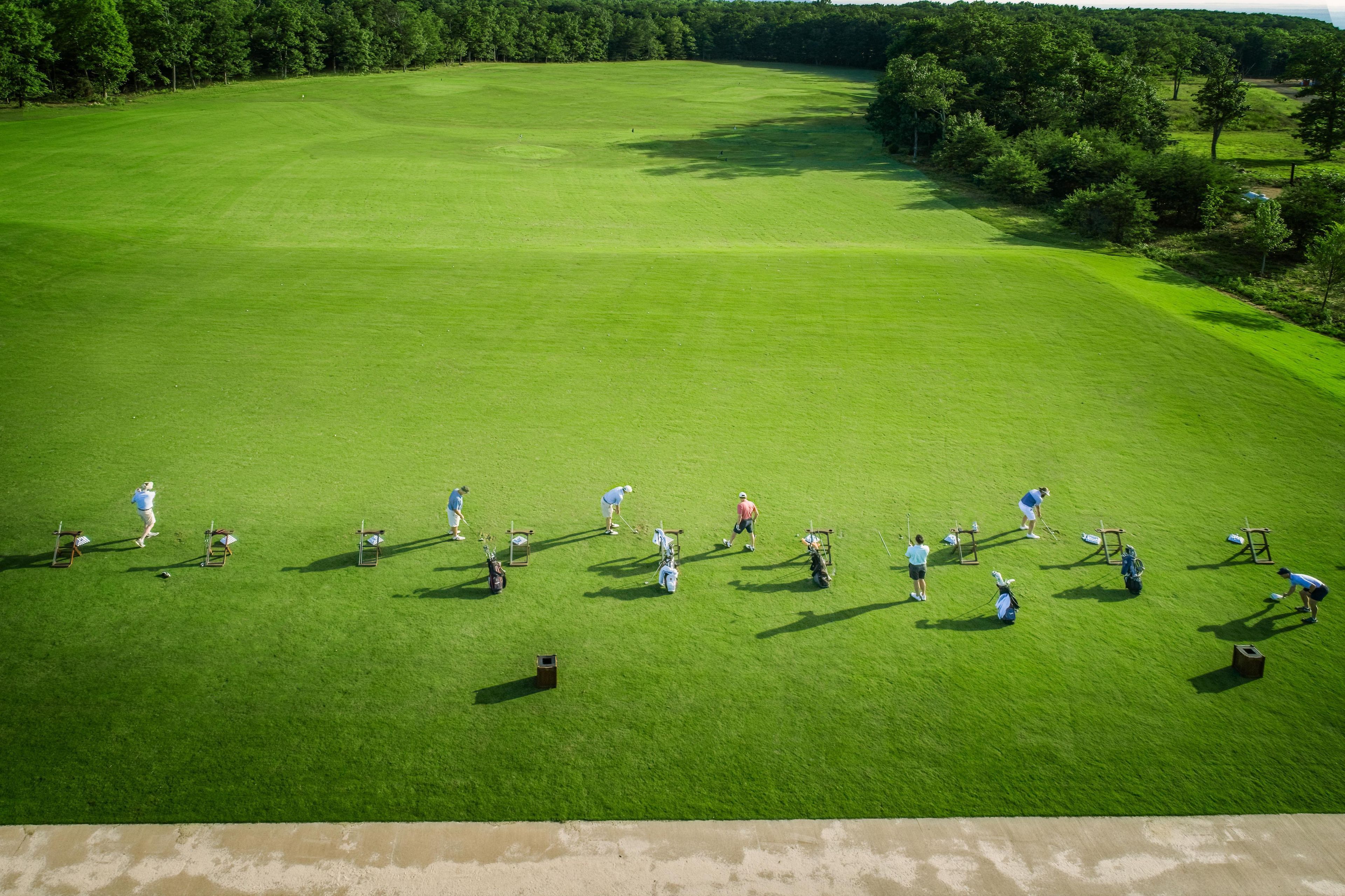 An aerial view of a golf course with players and equipment.