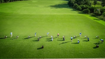 An aerial view of a golf course with players and equipment.