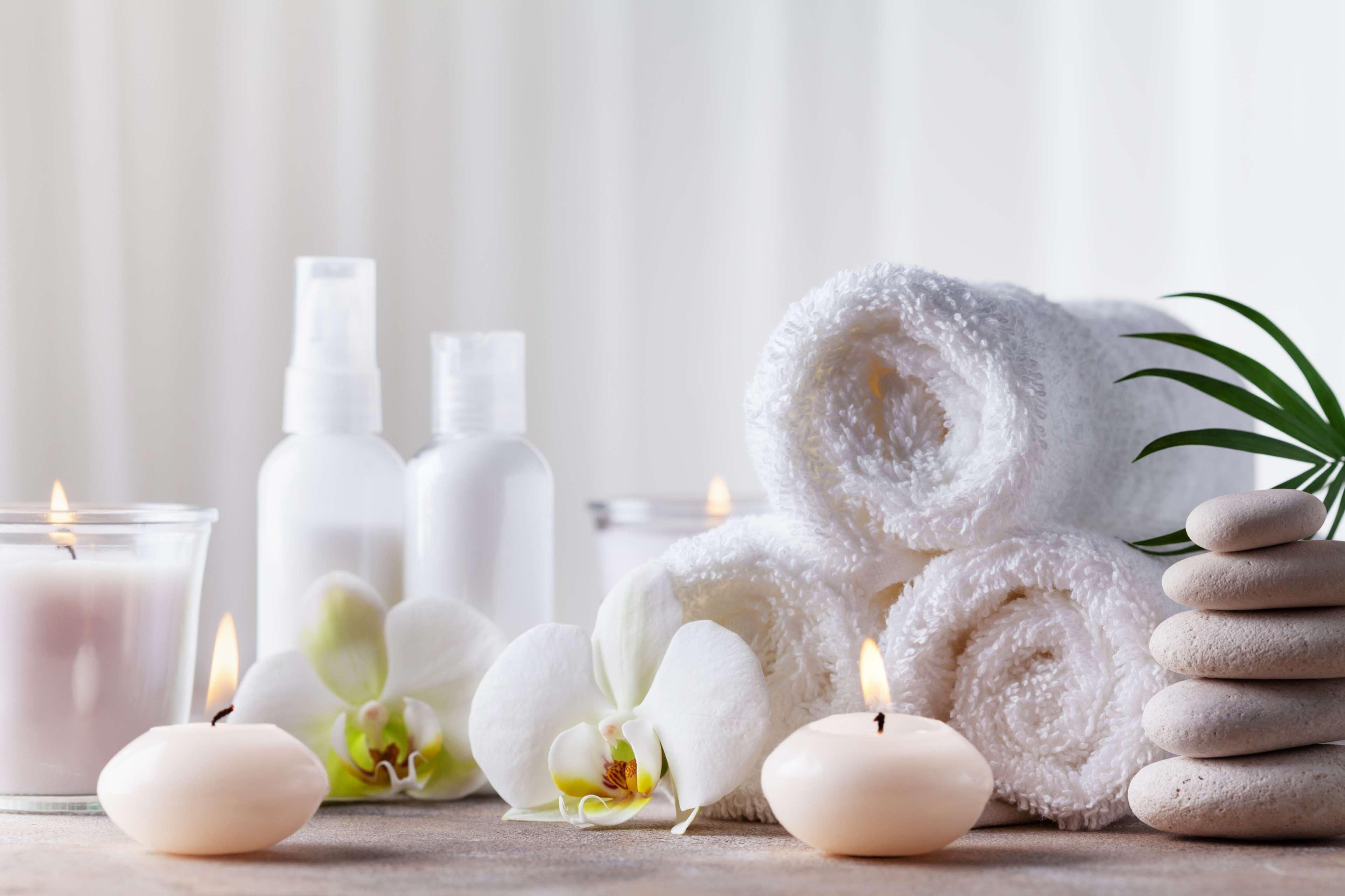 A spa setting with candles, white towels, and spa products.