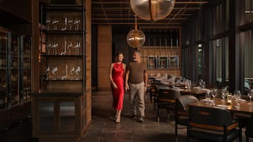 L’intérieur d’un restaurant, avec un meuble à vin, des tables et un grand luminaire suspendu.