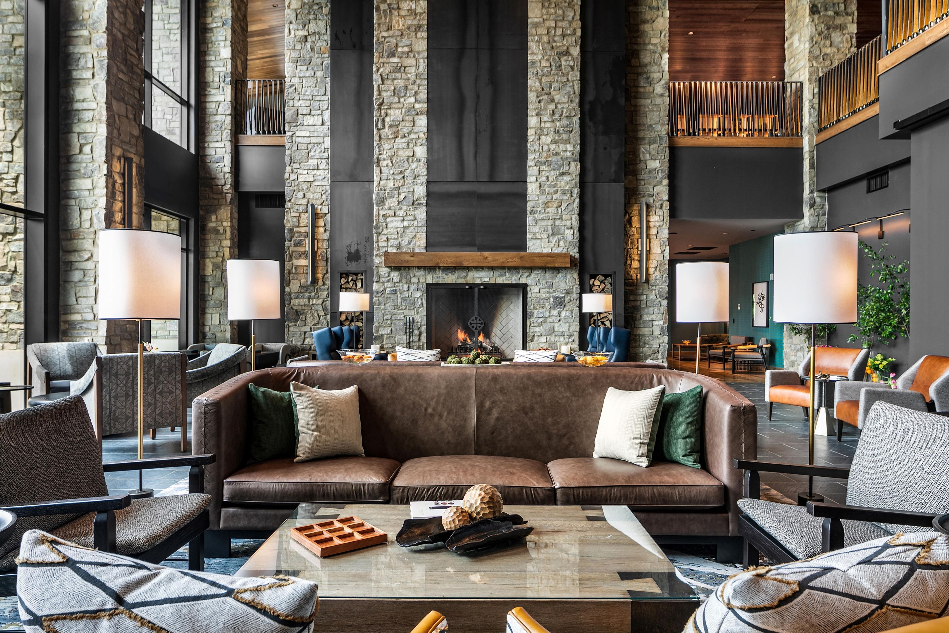 A modern lounge area with a stone fireplace, leather sofas, and contemporary lighting fixtures.