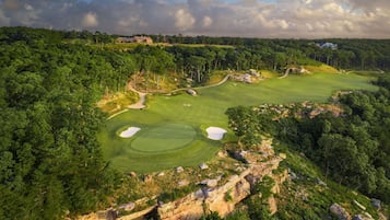 Un campo de golf con múltiples hoyos, rodeado de un bosque denso y terreno rocoso.
