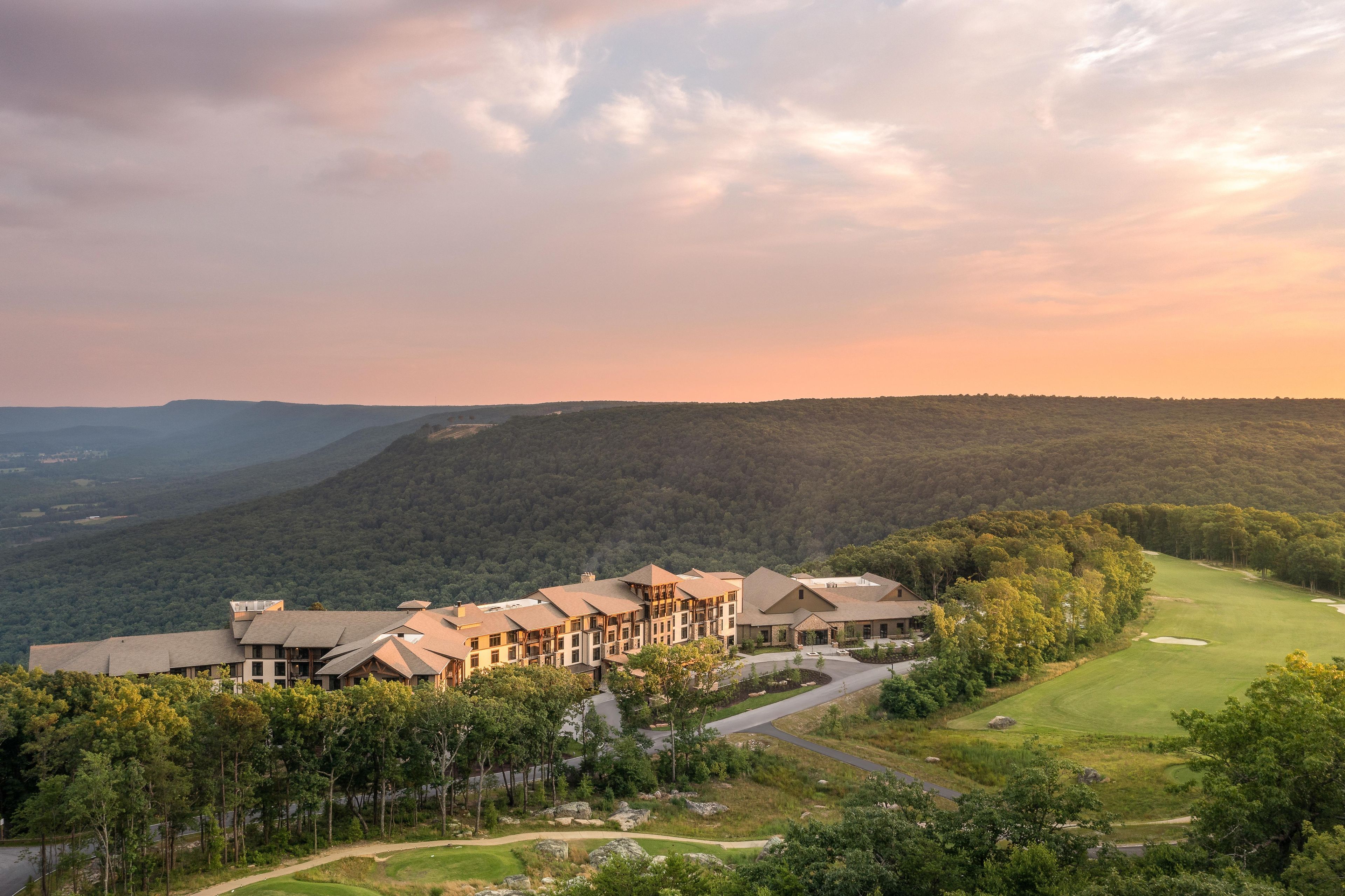 A large hotel with multiple buildings, surrounded by lush greenery and a golf course.
