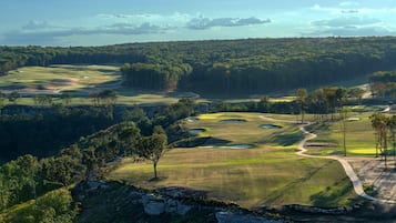 A golf course with multiple holes, trees, and a clear sky.