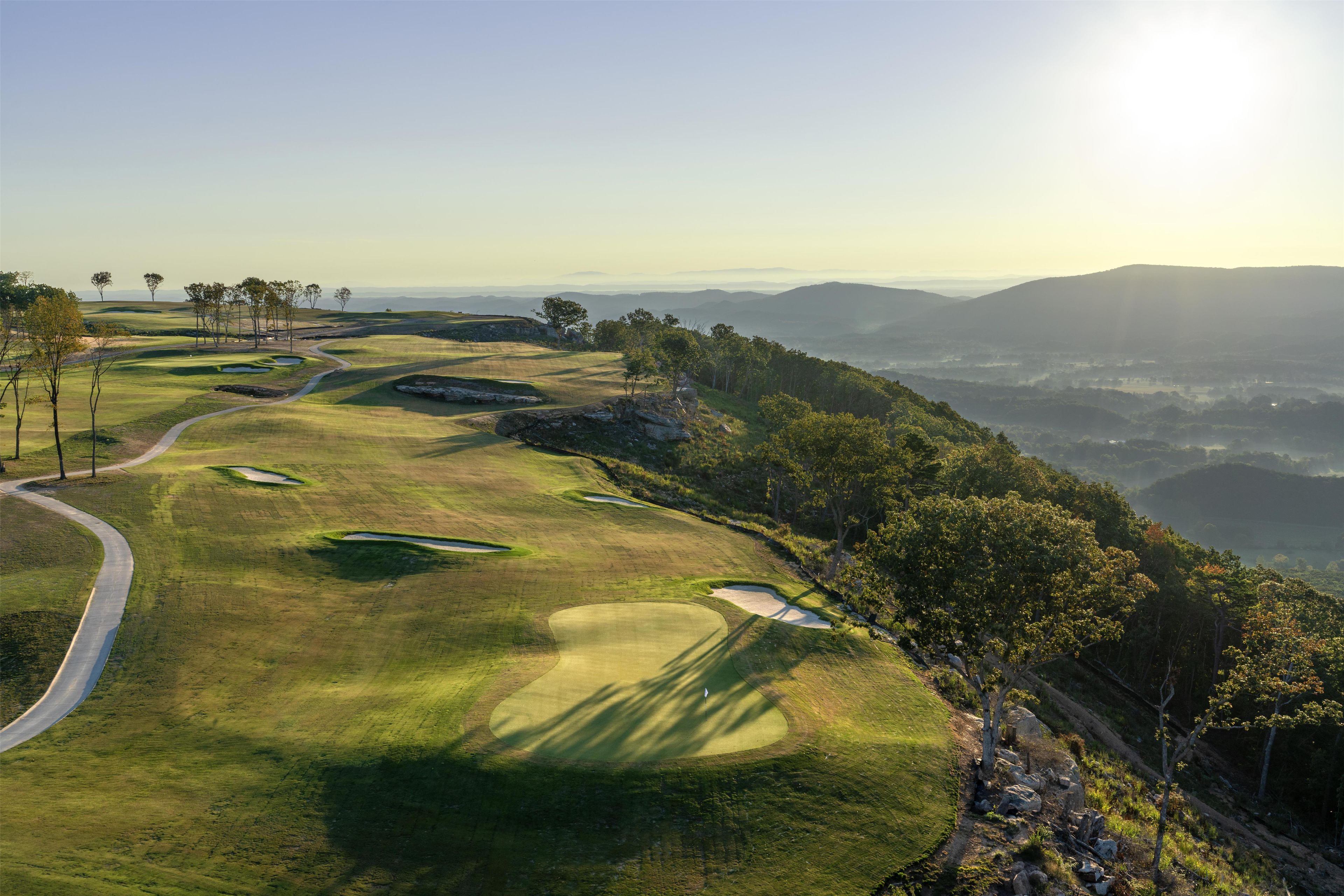 A golf course with a winding path, sand bunkers, and trees.