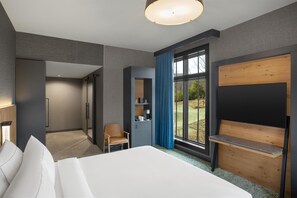 A modern hotel room with a large bed, a desk, a chair, a wardrobe, and a large window with a view of the outdoors. - Cloudland Mclemore Resort Lookout Mountain Curio (Rising Fawn)