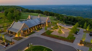 A large, stone building with a sloped roof, surrounded by a well-maintained lawn and a golf course in the background. - Cloudland Mclemore Resort Lookout Mountain Curio (Rising Fawn)