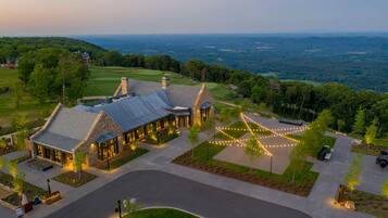 A large, stone building with a sloped roof, surrounded by a well-maintained lawn and a golf course in the background.
