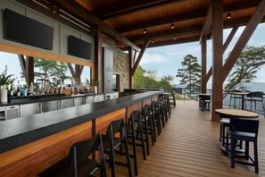 Un espace bar doté d’un long comptoir, de nombreux tabourets et offrant une vue sur l’extérieur.