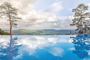 Vista clara de una piscina con reflejos de árboles y montañas.