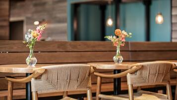 A restaurant interior with wooden benches and tables, each with a vase of flowers.