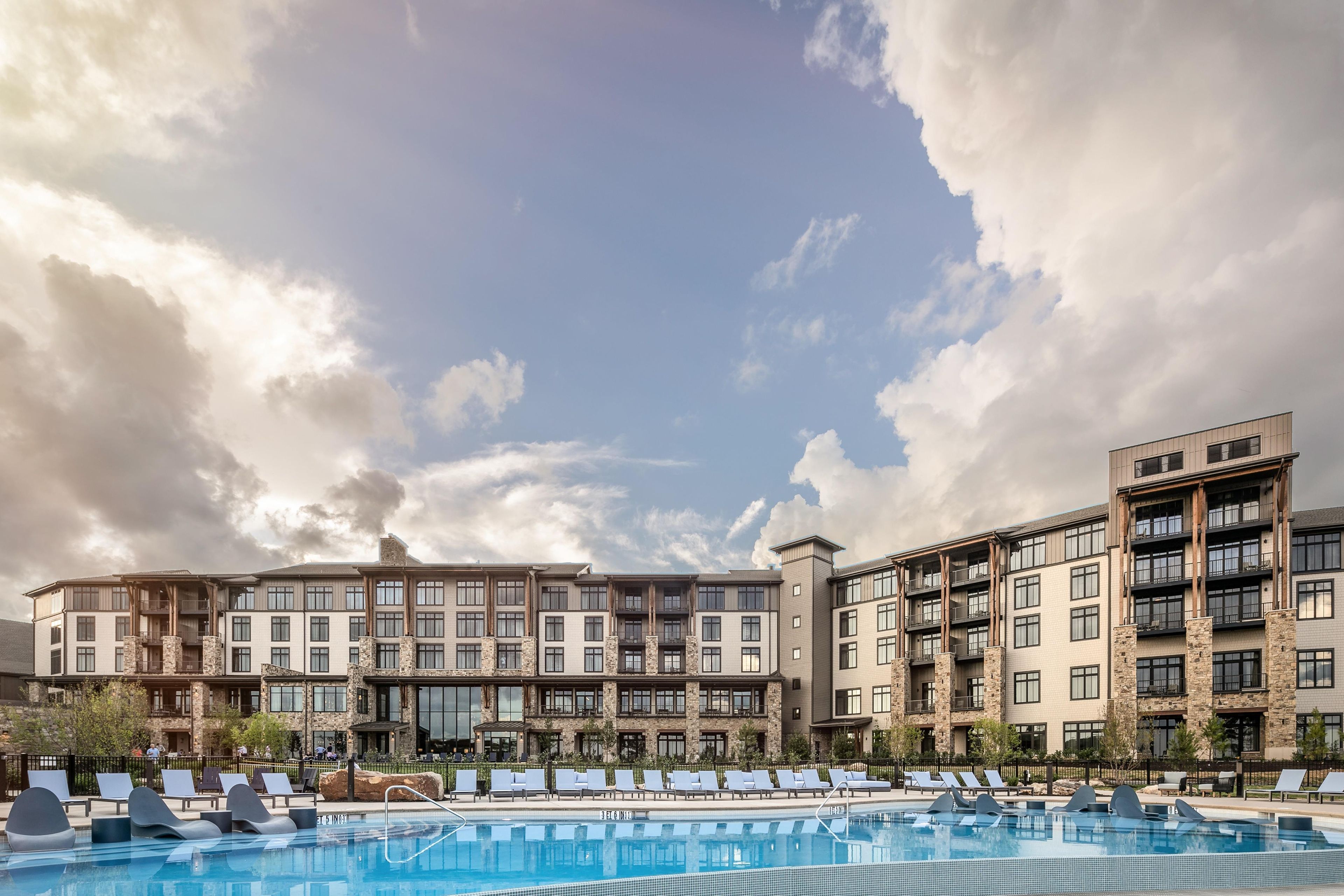 Un hotel con piscina, varios balcones y un diseño arquitectónico moderno.