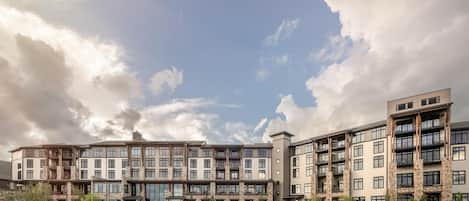 A hotel with a swimming pool, multiple balconies, and a modern architectural design.