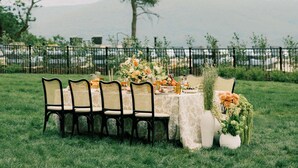 Un espace de restauration en plein air, avec une table et des chaises, entouré de verdure et délimité par une clôture.