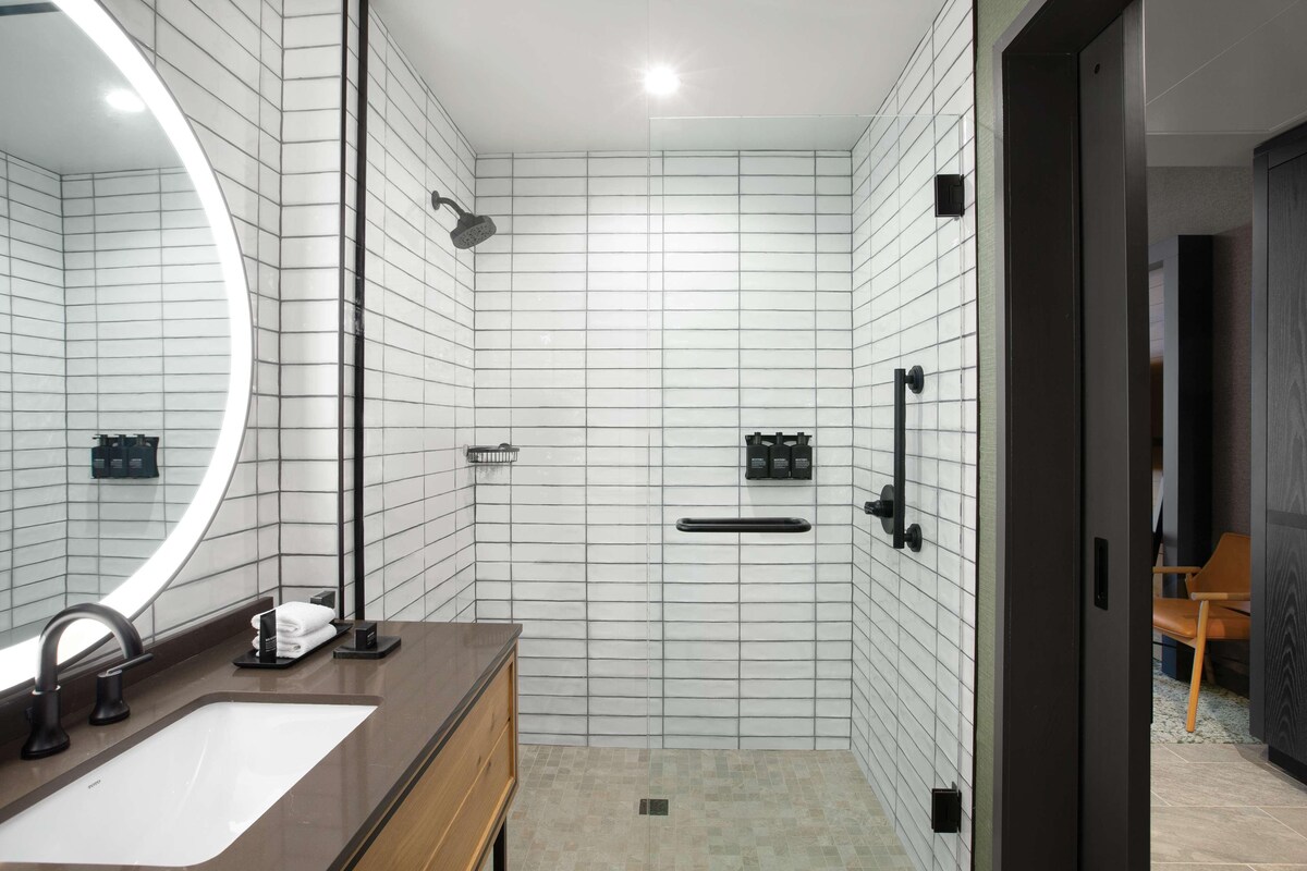 Une salle de bain moderne avec un grand miroir, un lavabo, une douche et des toilettes.