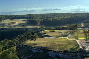 Een golfbaan met diverse holes, bomen en een heldere lucht.