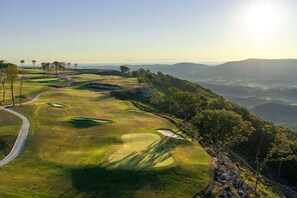 Un parcours de golf avec un chemin sinueux, des bunkers de sable et des arbres.
