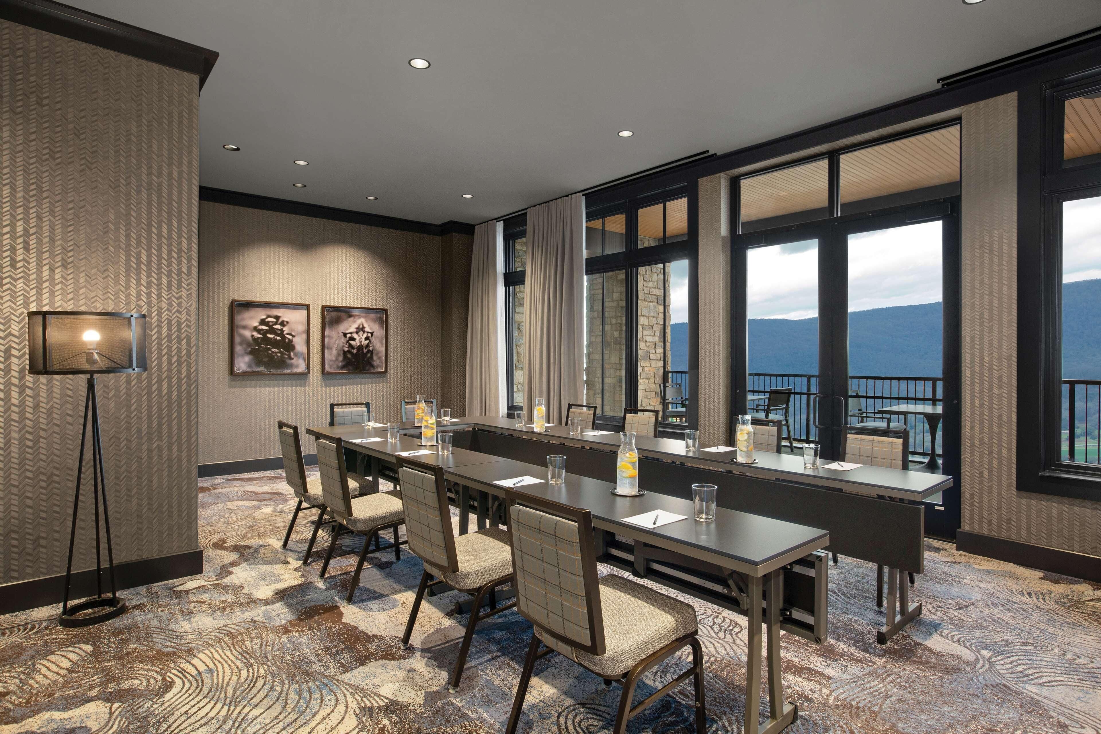 A conference room with a long table, chairs, and a view of the mountains through large windows.