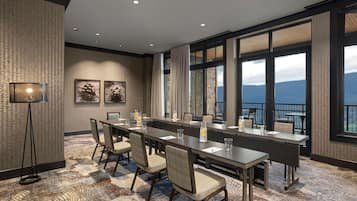 A conference room with a long table, chairs, and a view of the mountains through large windows.
