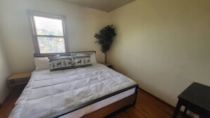Une chambre à coucher avec un lit, une table de chevet, une fenêtre et une petite table.
