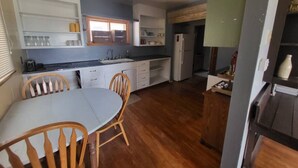 Une cuisine de taille réduite avec un coin repas, des chaises en bois et un réfrigérateur.