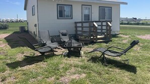 Une petite maison dotée d’un patio aménagé avec du mobilier d’extérieur et un barbecue.