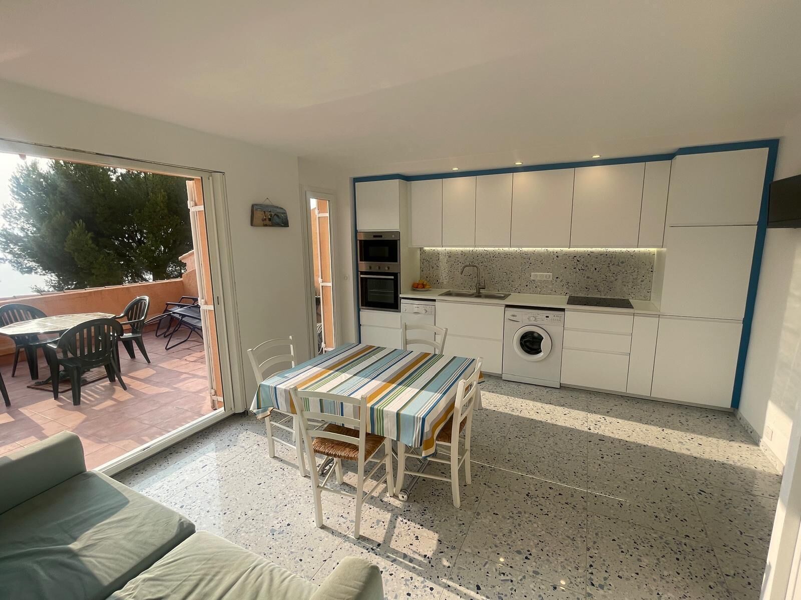 A compact living space with a dining area, kitchenette, and a view of the outdoors.