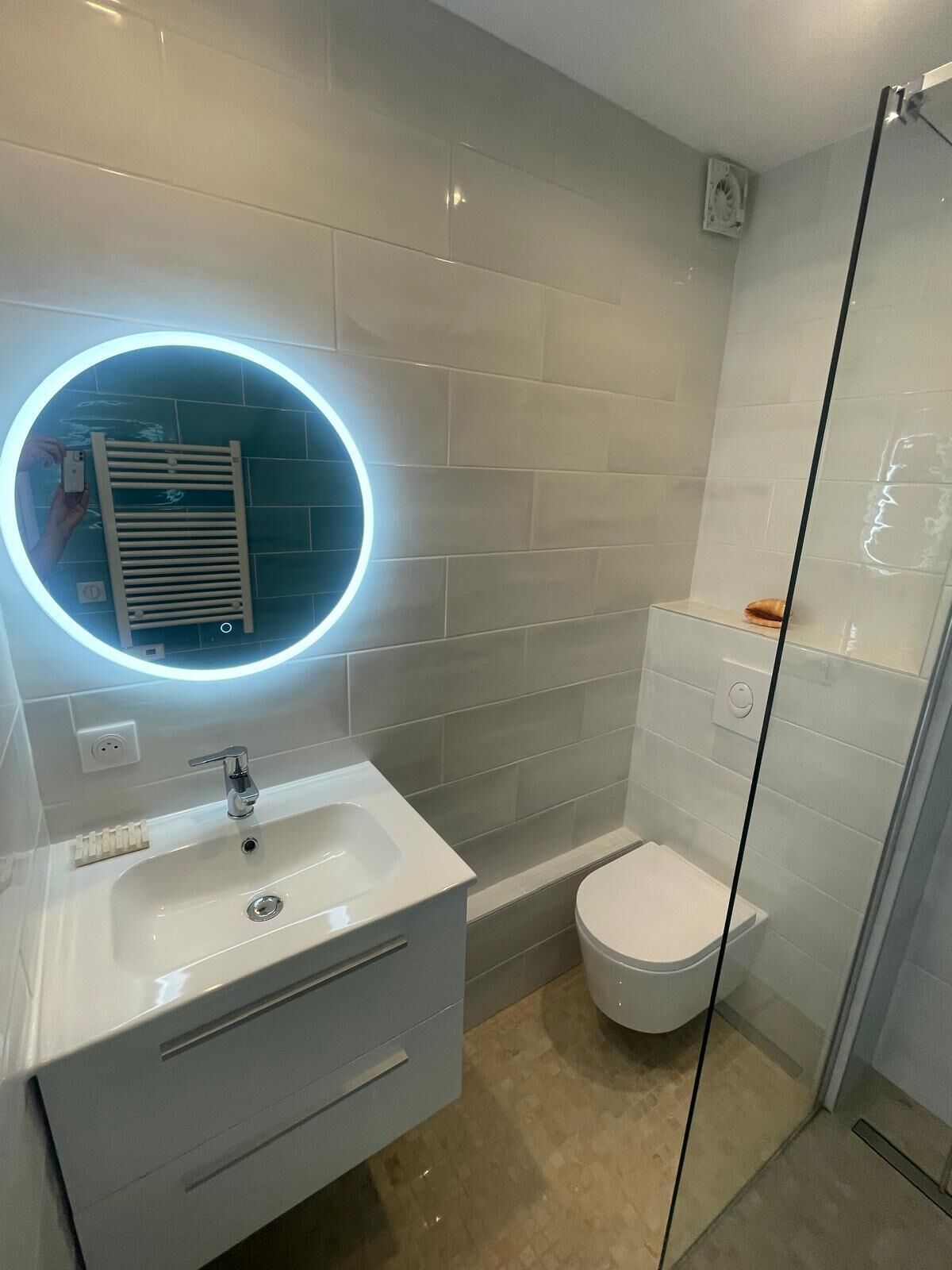Une salle de bain moderne avec un lavabo blanc, des toilettes et une douche à parois de verre.