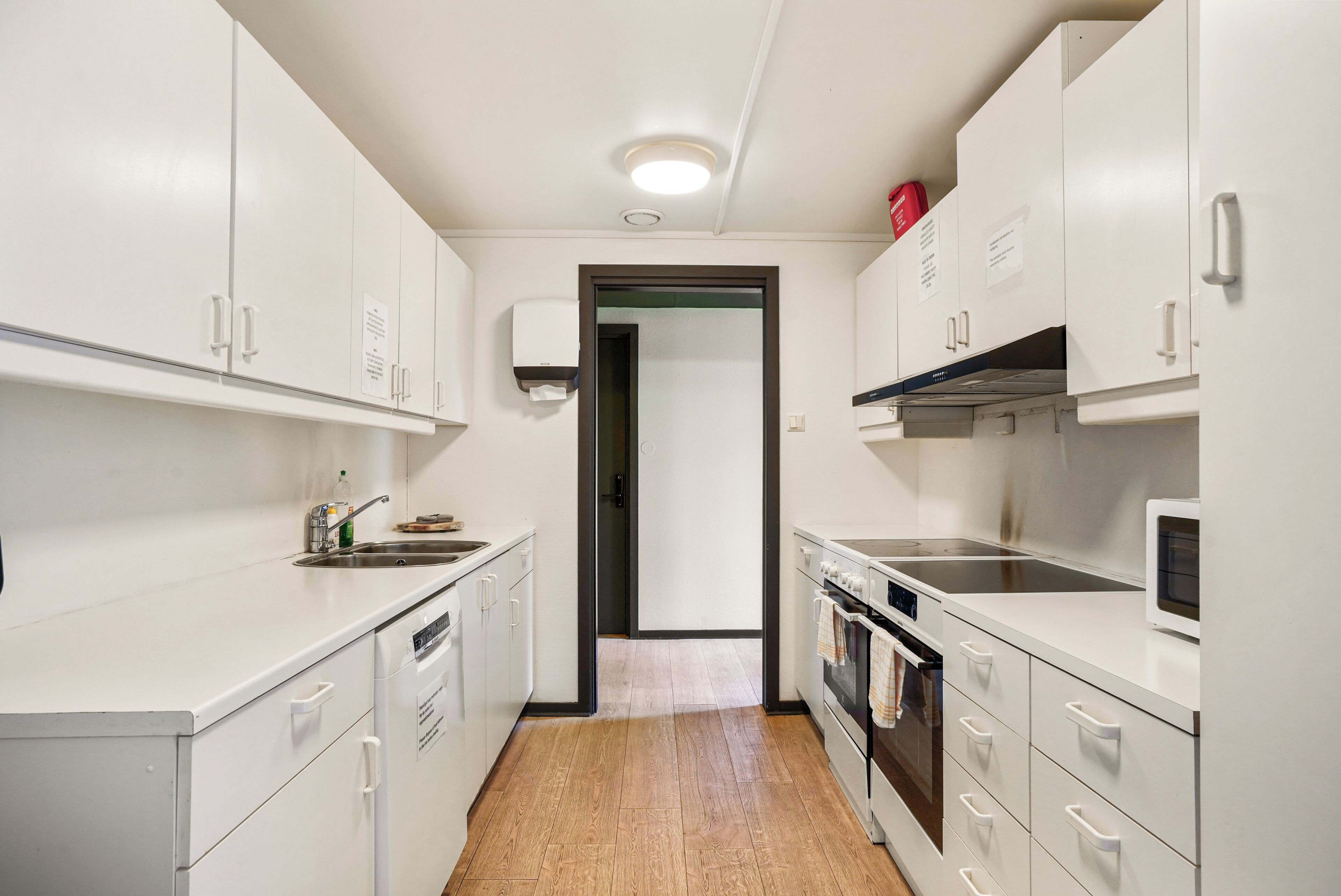 A modern kitchen with white cabinets, a built-in oven, and a microwave.
