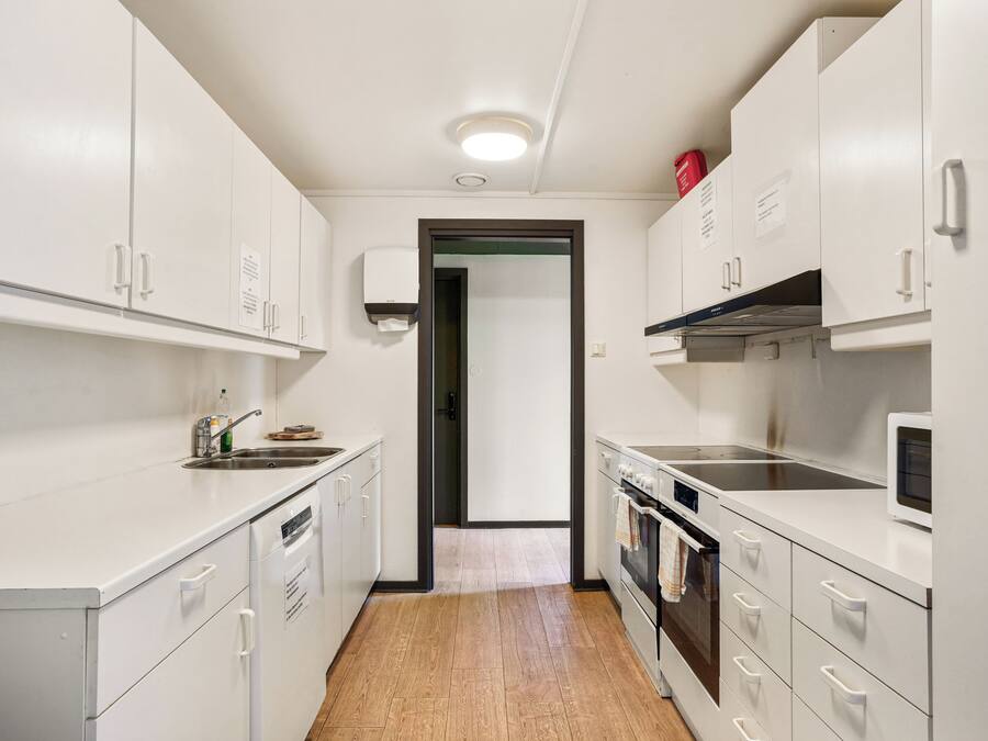 A modern kitchen with white cabinets, a built-in oven, and a microwave.