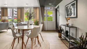 A modern dining area with a round table, chairs, and a potted plant. - A-11 (Ålesund)