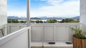 A balcony with a view of snow-capped mountains, a wooden bench, and a potted plant. - A-11 (Ålesund)