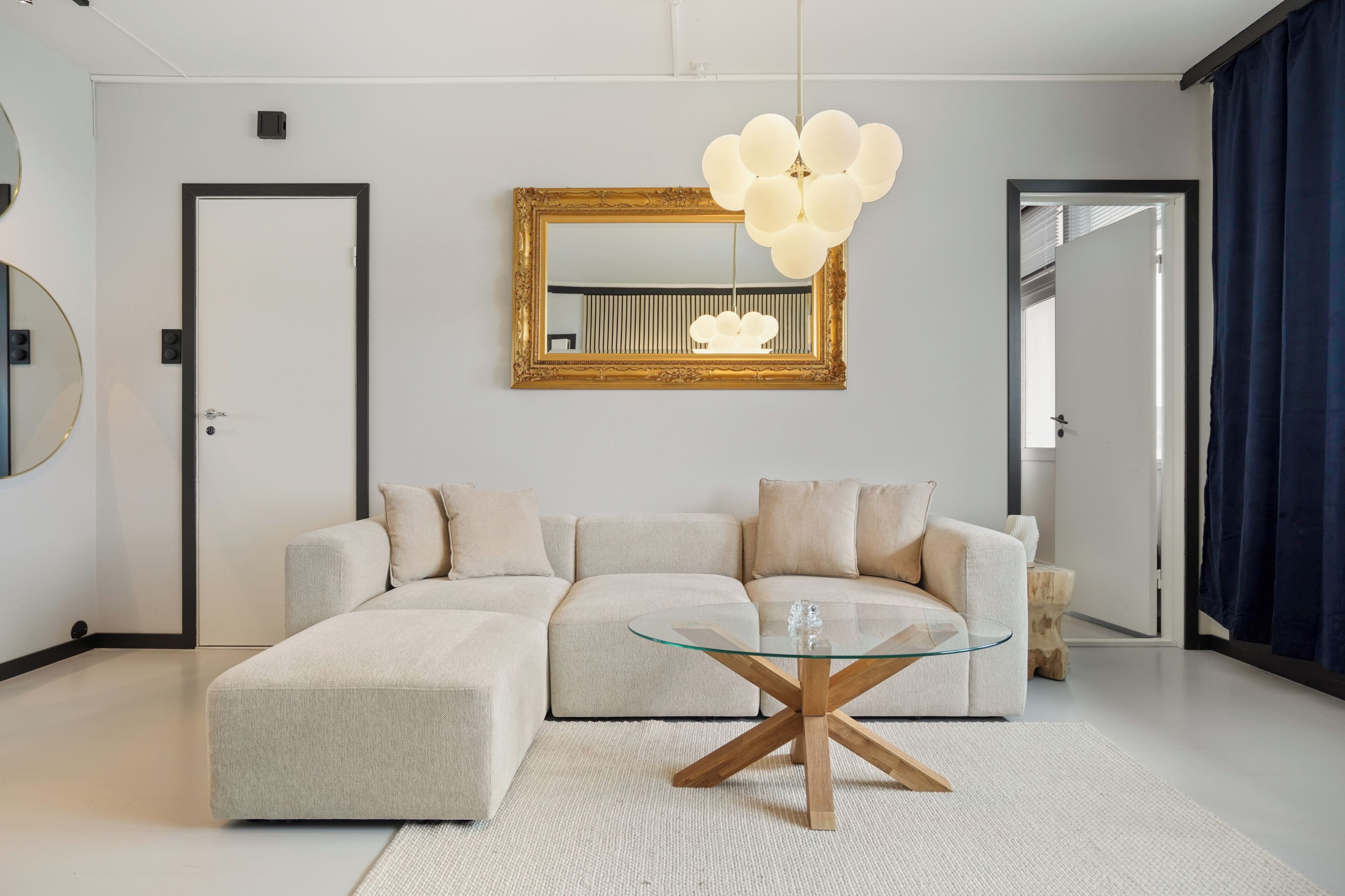 Una sala de estar moderna con un sofá modular, una mesa de centro de vidrio, un espejo grande y una lámpara de araña original.