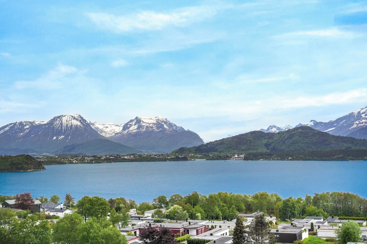 A lakeside view with mountains in the background and a residential area in the foreground.