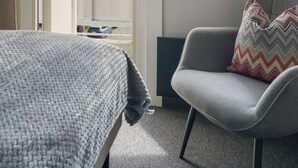 A room with a bed, a grey armchair, and a view of mountains through a window. - A-11 (Ålesund)